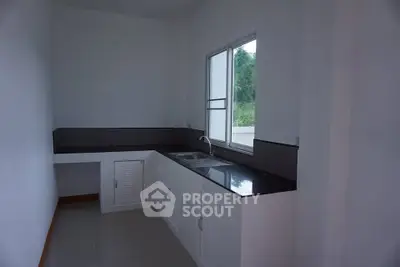Modern minimalist kitchen with sleek black countertops and white cabinetry.