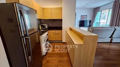 Modern open-layout kitchen with stainless steel appliances and cozy living room view.