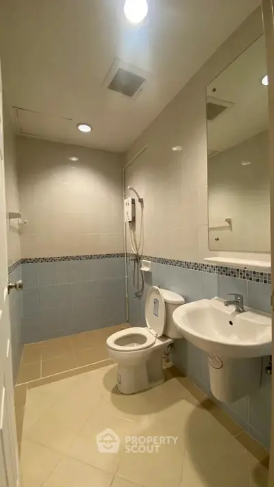 Modern bathroom with sleek fixtures and neutral tiles, featuring a shower and toilet.