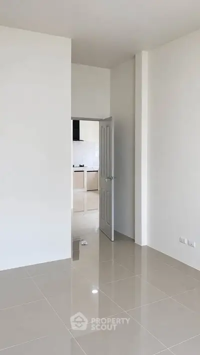 Spacious modern apartment with sleek tiled flooring and open kitchen layout.