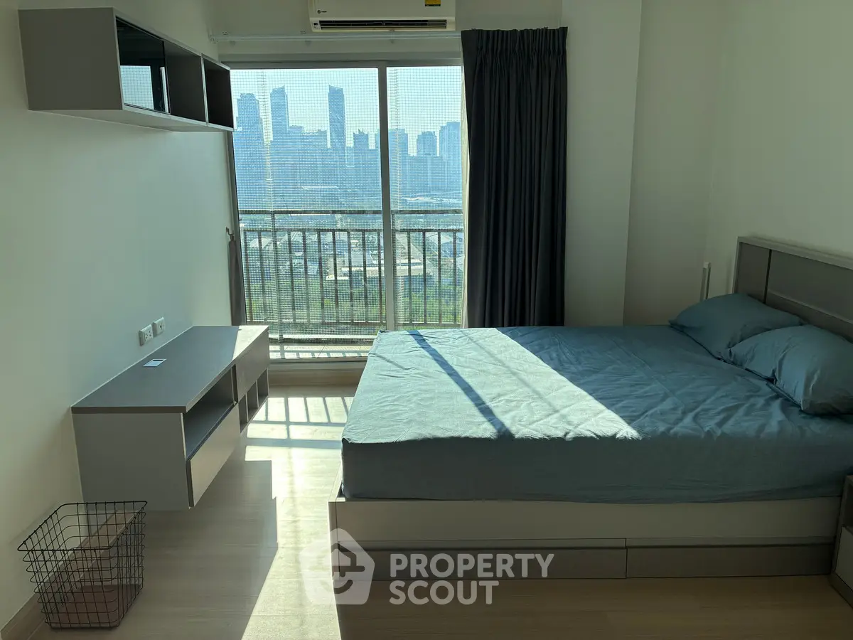 Modern bedroom with city view, featuring sleek furniture and large windows for natural light.