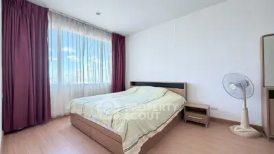Bright and airy bedroom with large window and modern furnishings in a high-rise apartment.