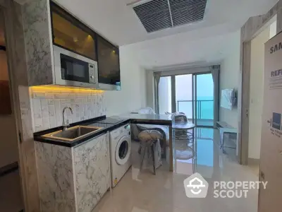 Sleek modern kitchen with marble countertops, stainless steel appliances, and a breathtaking ocean view from the adjoining balcony.