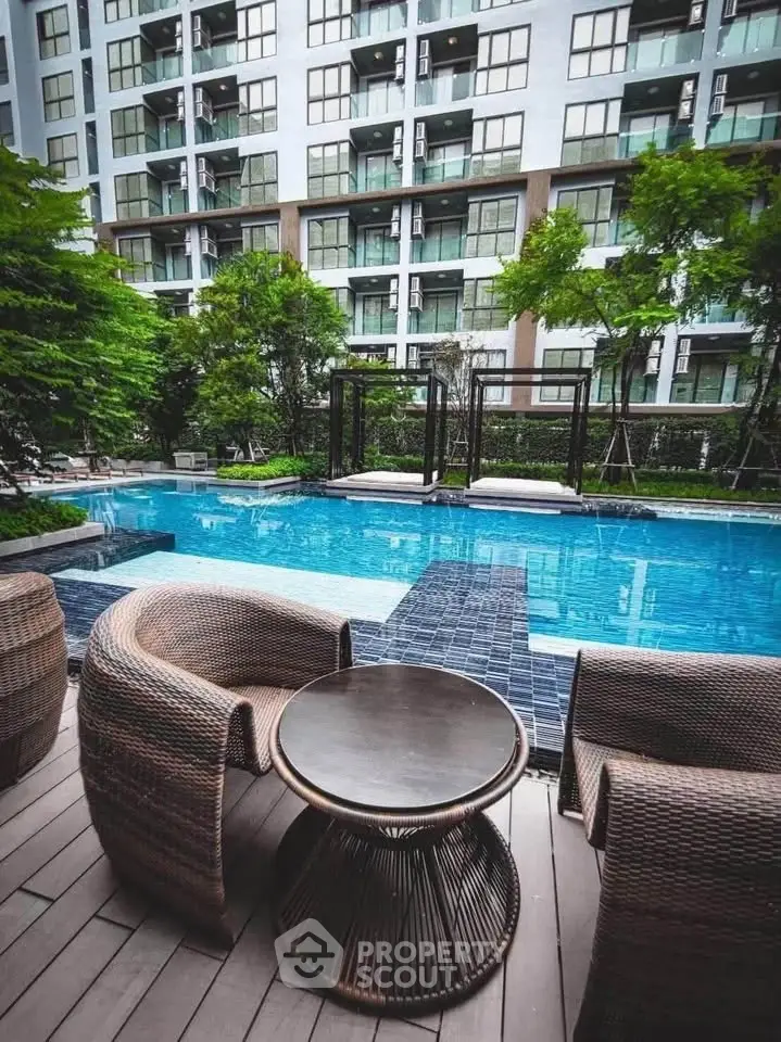 Luxurious apartment complex with a stunning pool and stylish outdoor seating area.