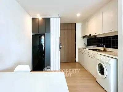 Modern kitchen with sleek appliances and washing machine in a stylish apartment.