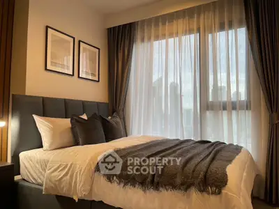 Cozy bedroom with elegant decor and city view through large window.