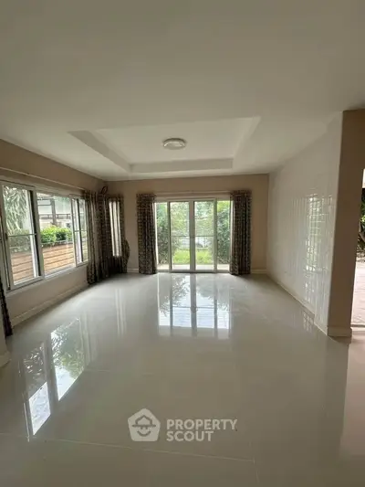 Spacious living room with large windows and garden view, perfect for natural light lovers.