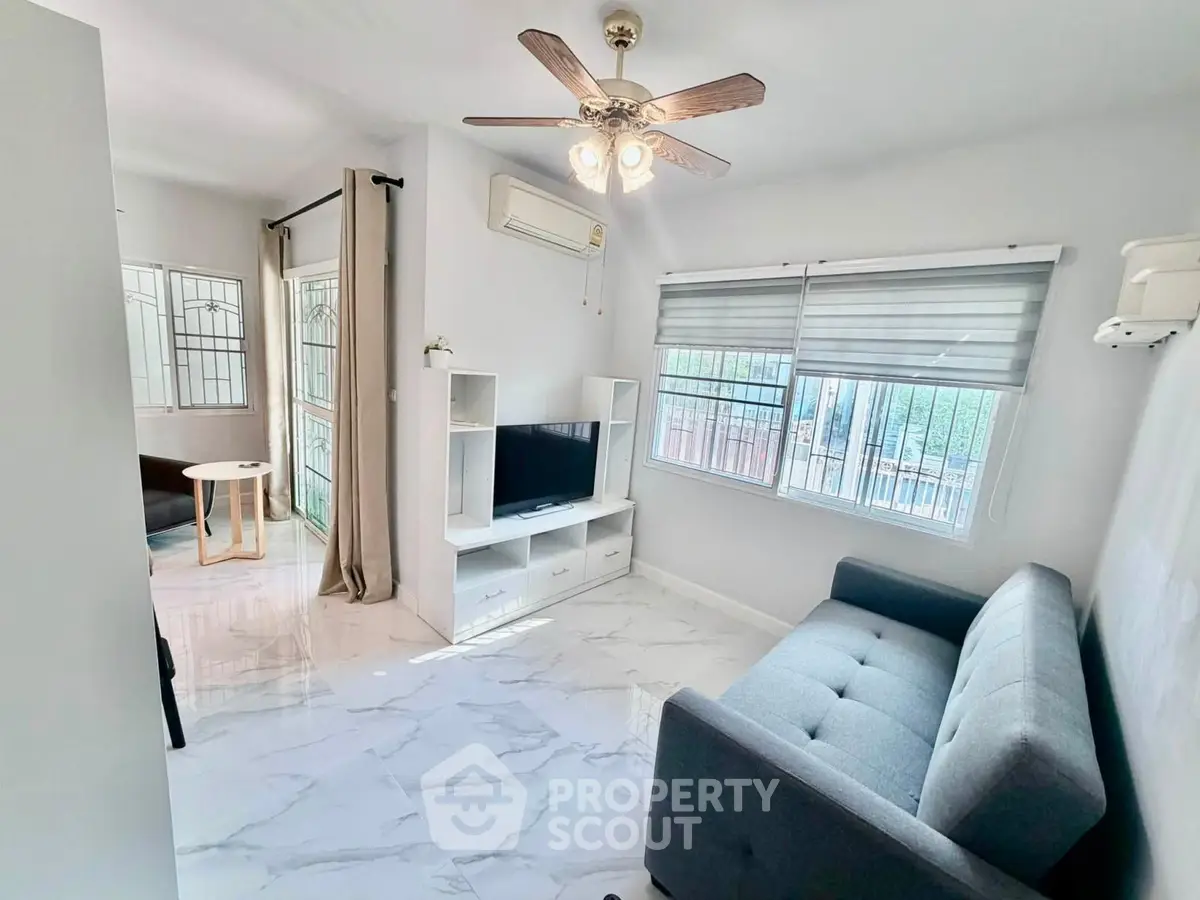 Bright living room with modern decor, ceiling fan, and large windows for natural light.