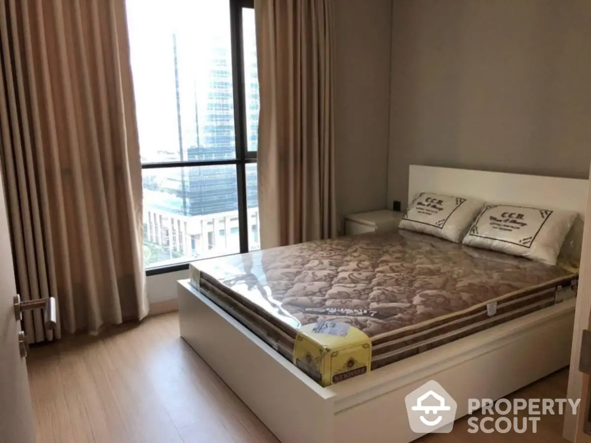 Modern bedroom with large window and city view, featuring a comfortable bed and stylish decor.