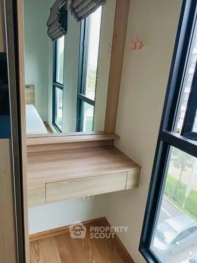 Modern bedroom with wooden vanity and large windows offering natural light