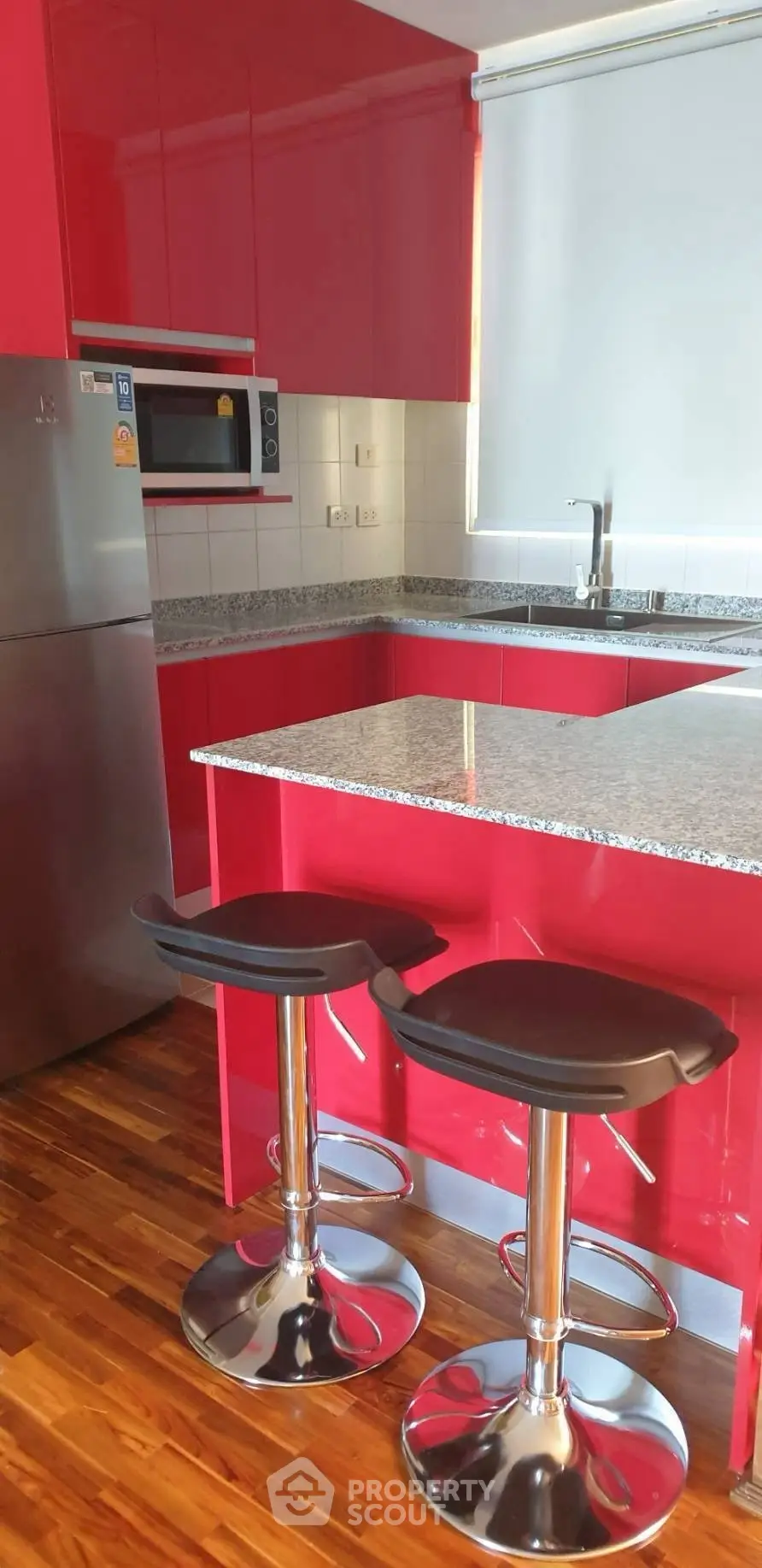 Modern kitchen with vibrant red cabinets and sleek bar stools