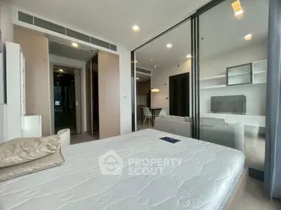 Modern bedroom with glass partition and view into stylish living room.