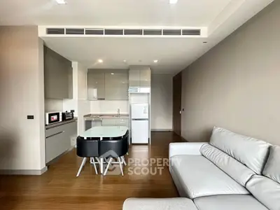 Modern open-layout kitchen and living room with sleek furniture and wooden flooring.
