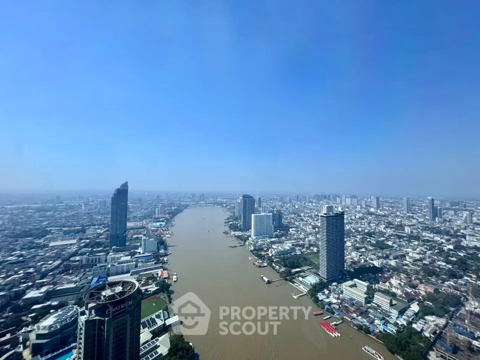 Stunning aerial view of a vibrant cityscape with river and skyscrapers under a clear blue sky.