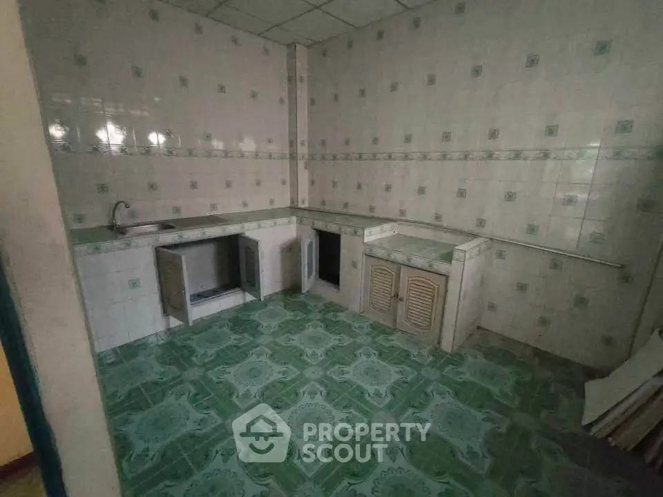 Spacious kitchen with tiled walls and floor, featuring ample storage and counter space.