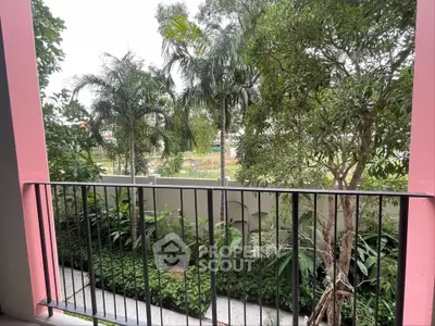Charming garden view from a cozy balcony with lush greenery and palm trees.