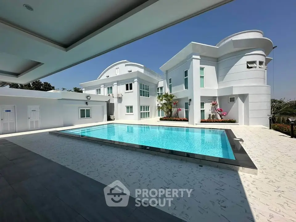 Luxurious modern villa with pristine swimming pool and elegant architecture under clear blue sky.