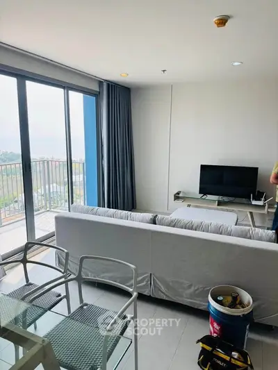 Modern living room with balcony view, featuring sleek furniture and natural light.