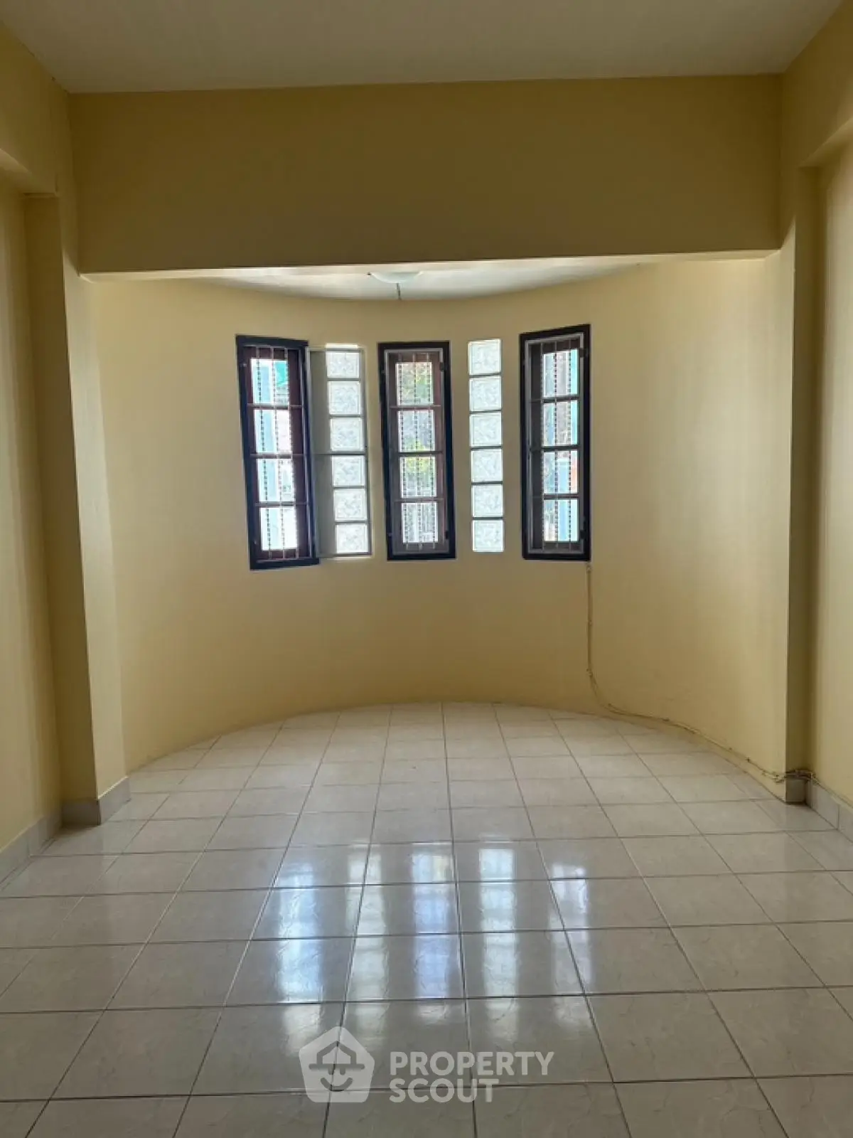 Spacious empty room with unique curved window design and tiled flooring