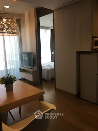Modern apartment interior with open living area and view into bedroom, featuring stylish decor and natural light.
