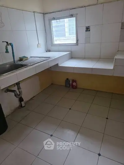 Spacious kitchen with tiled countertops and window, ideal for culinary creativity.