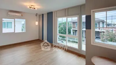 Spacious empty room with large windows and wooden flooring, offering a bright and airy atmosphere.