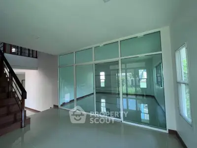 Spacious modern interior with glass partition and staircase, ideal for open living concepts.