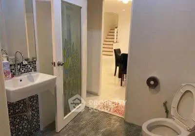 Modern bathroom with open door leading to dining area and staircase