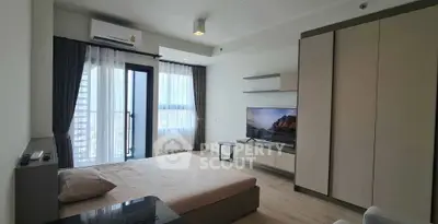 Modern bedroom with large window and city view, featuring sleek furniture and a mounted TV.