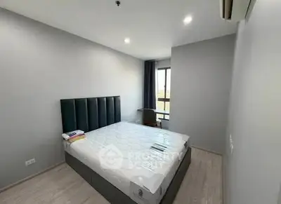 Modern bedroom with minimalist design and large window offering natural light.