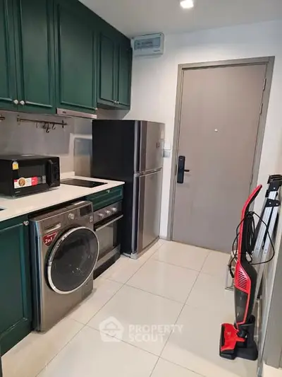 Modern kitchen with green cabinets, stainless steel appliances, and sleek tile flooring.