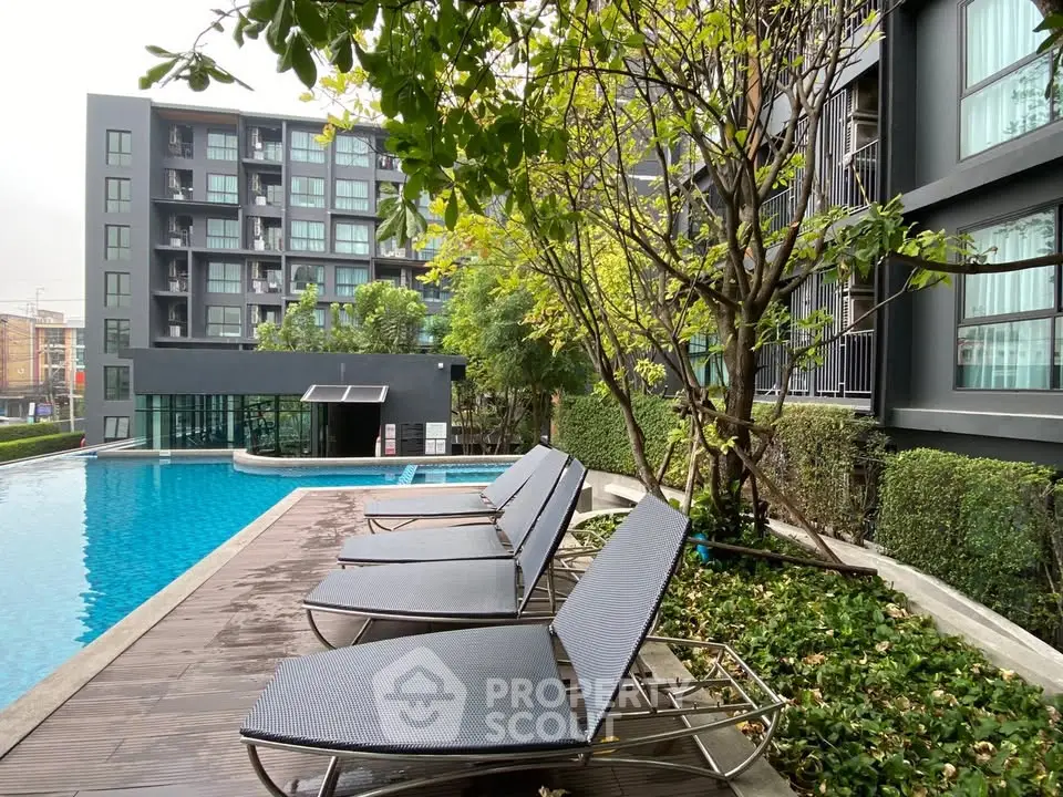 Modern apartment complex with poolside lounge chairs and lush greenery