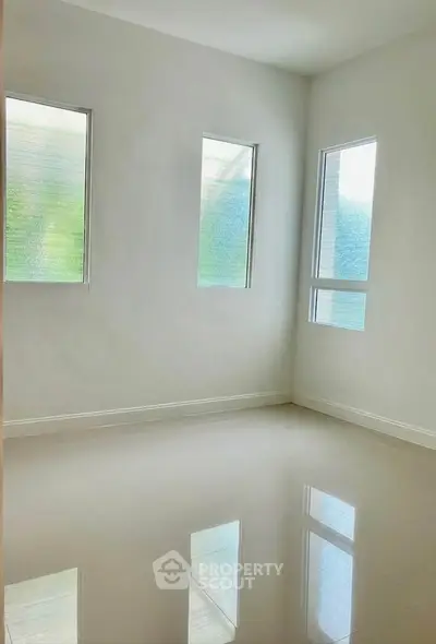 Bright empty room with glossy tiled floor and three large windows, perfect for customization.