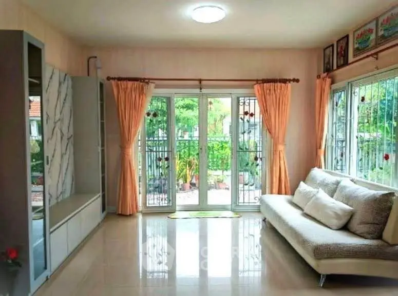 Bright and spacious living room with large windows and garden view, perfect for relaxation.