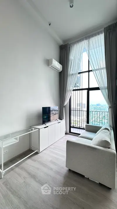 Modern living room with high ceiling and large window offering stunning city view.