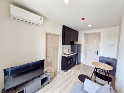 Modern compact living room with kitchenette, featuring sleek furniture and efficient use of space.