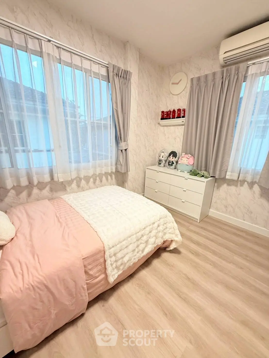 Cozy bedroom with soft pink bedding, elegant curtains, and stylish decor in a modern home.