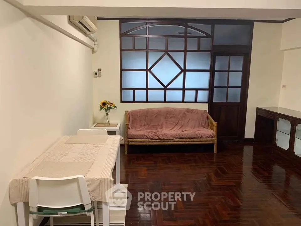 Cozy living room with wooden flooring, sofa, and dining area in a stylish apartment.