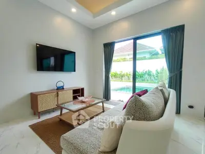 Modern living room with pool view, stylish furniture, and large sliding glass doors.
