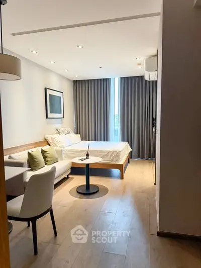 Modern bedroom with cozy seating area and large window for natural light.