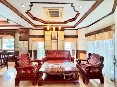 Luxurious living room with elegant wooden furniture and intricate ceiling design.