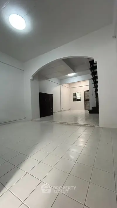 Spacious open-plan living area with tiled flooring and modern staircase, perfect for contemporary living.