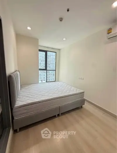Modern bedroom with large window and air conditioning in high-rise apartment.
