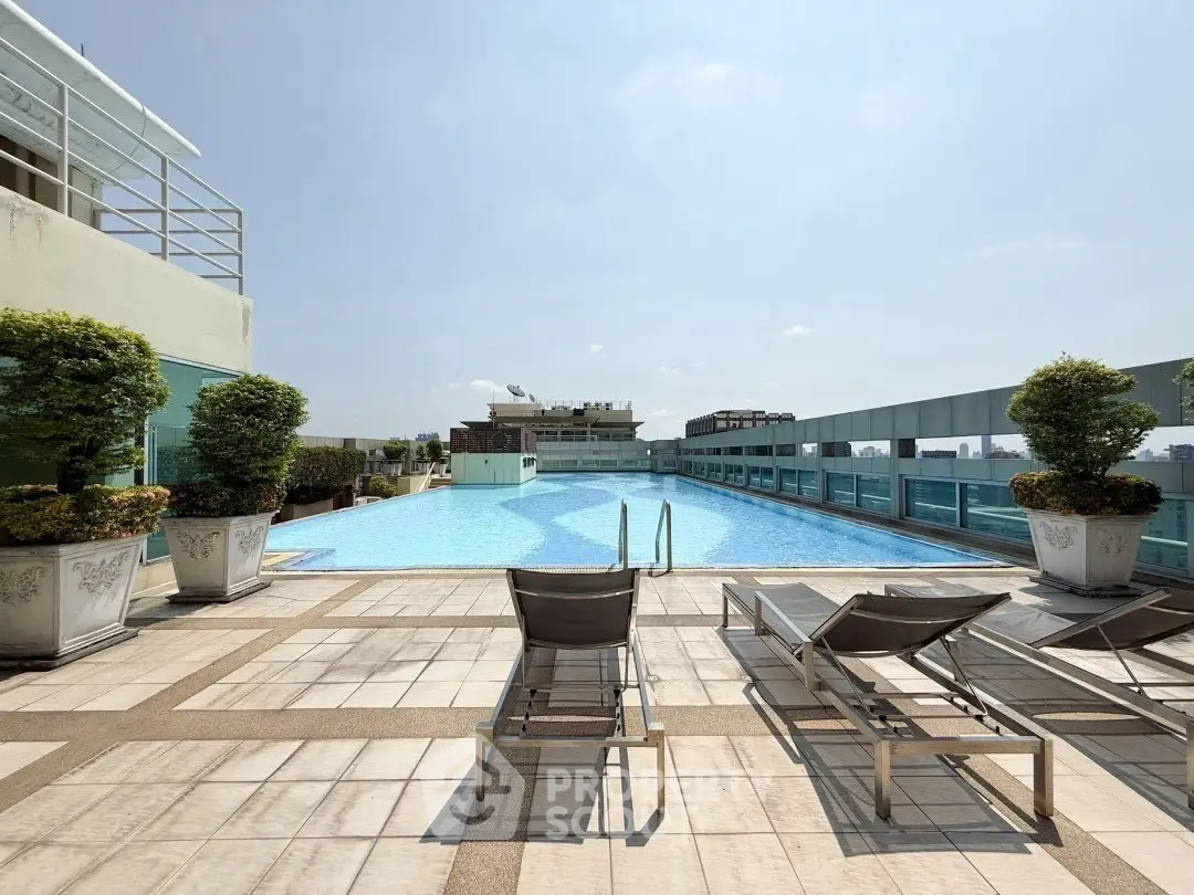Luxurious rooftop pool with sun loungers and city view, perfect for relaxation.