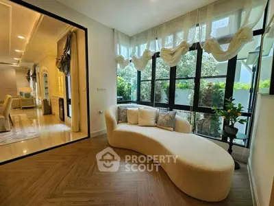Elegant living room with curved sofa and large windows offering garden view