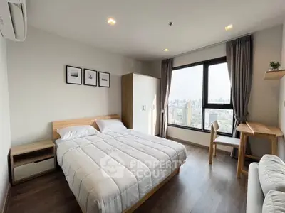 Modern bedroom with city view, featuring cozy bed and stylish decor.