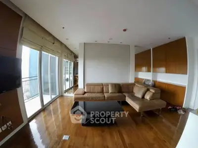 Spacious modern living room with elegant wooden flooring and large windows.