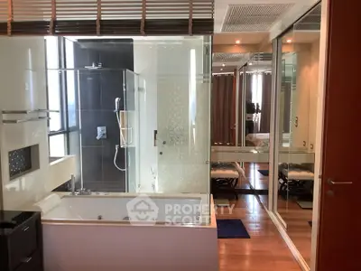 Luxurious bathroom with modern bathtub and glass shower enclosure in elegant apartment.