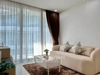 Elegant living room with plush sofa, sheer curtains, and modern decor in a bright apartment.