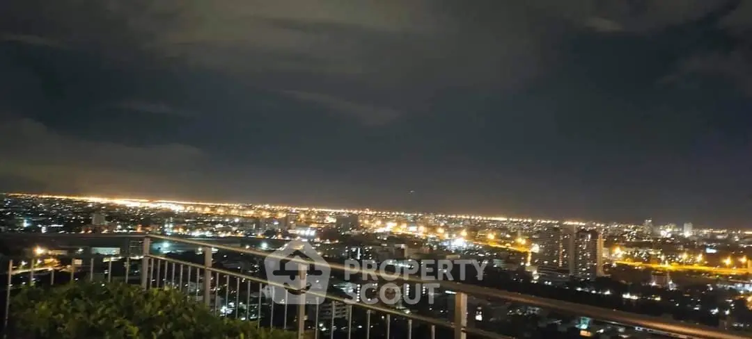 Stunning city skyline view from a rooftop at night with bright city lights.
